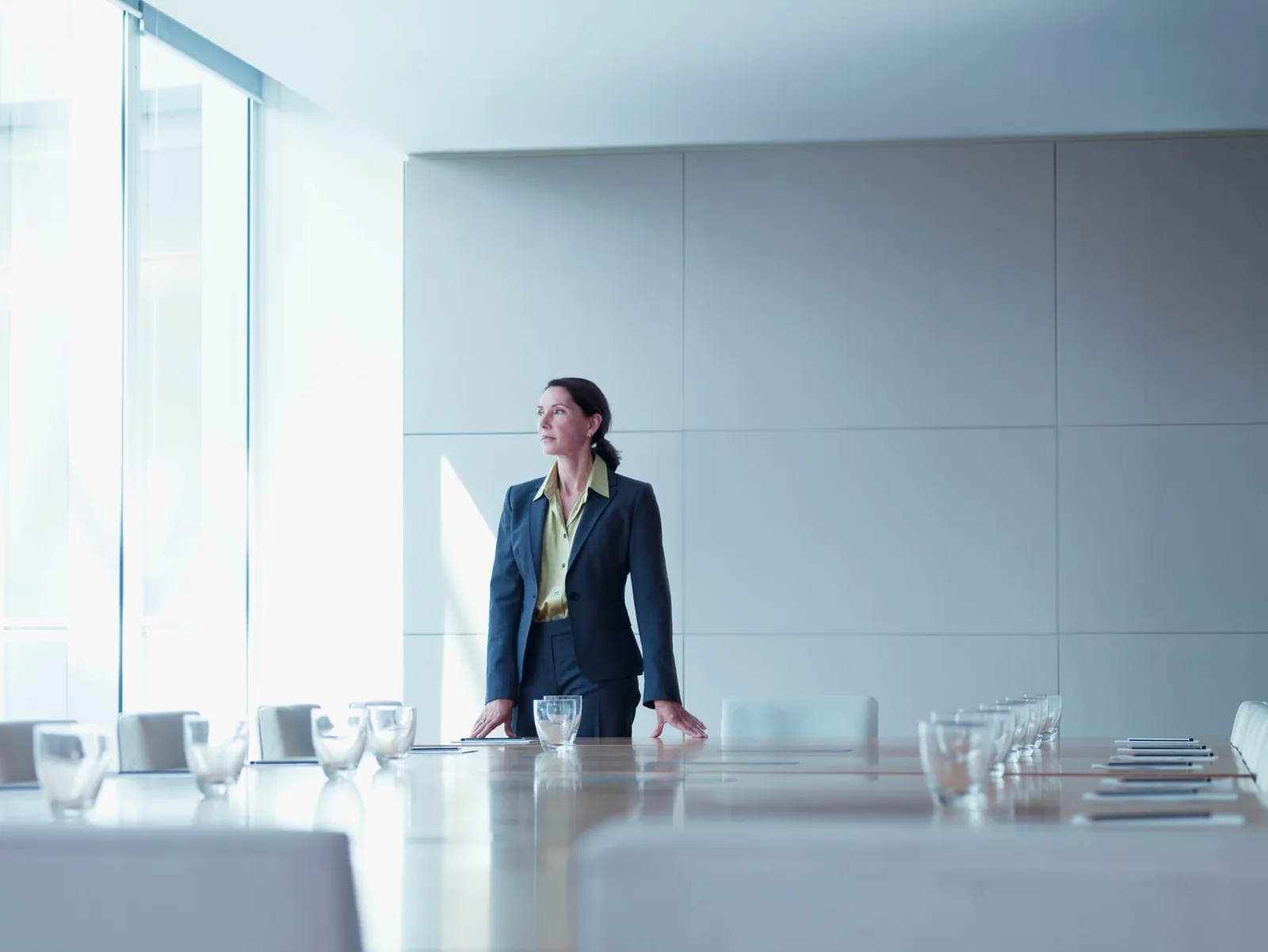 A woman standing beside a meeting table in a bright office