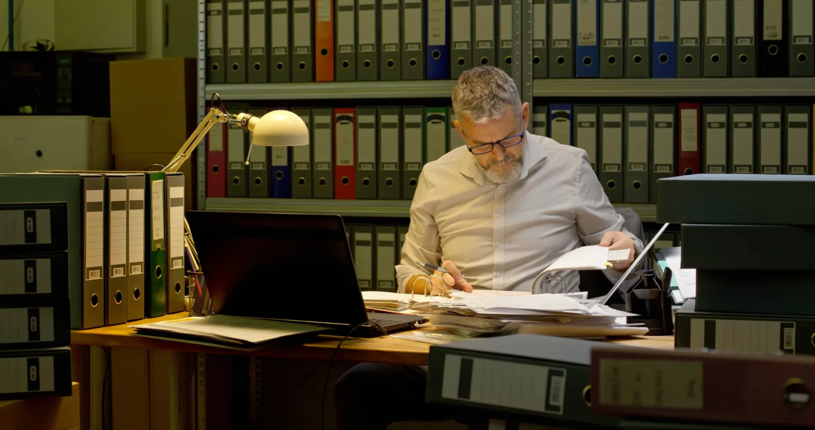 A man reviewing paperwork at a desk in an office