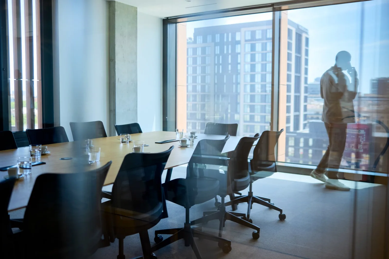 A glass-walled boardroom with a meeting table and office chairs