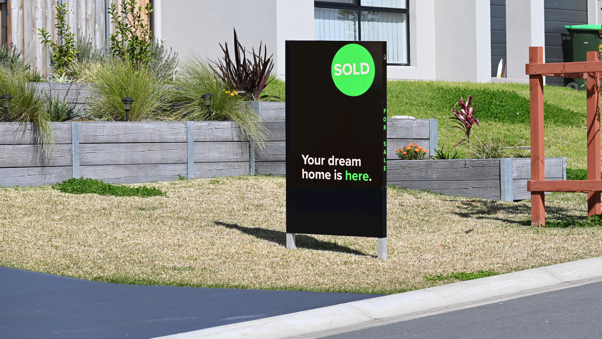 Real estate 'SOLD' sign in front of a suburban home