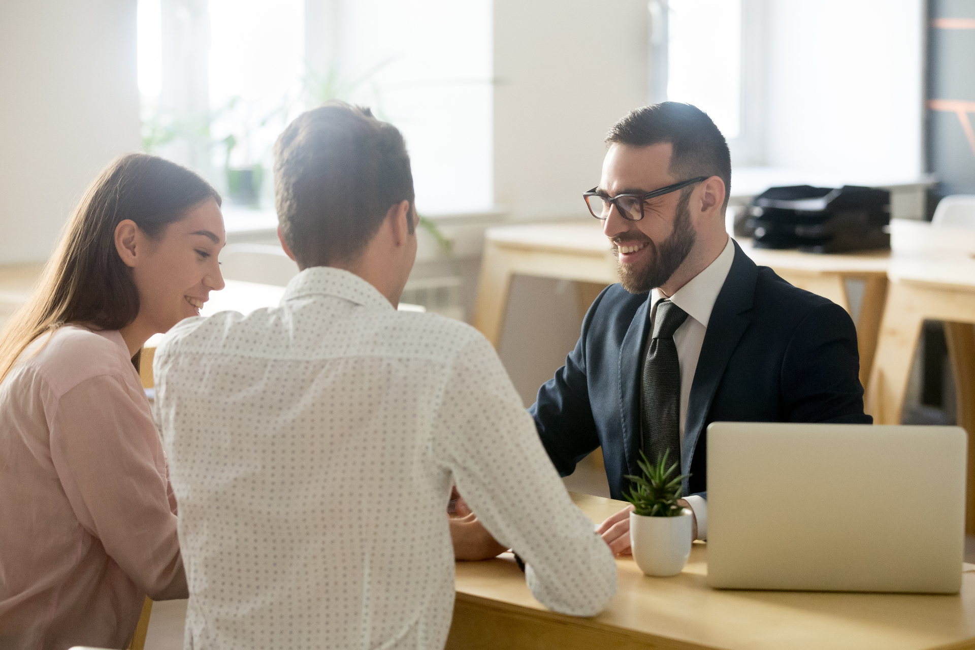 Two clients meeting across a desk with an employment lawyer in a bright office
