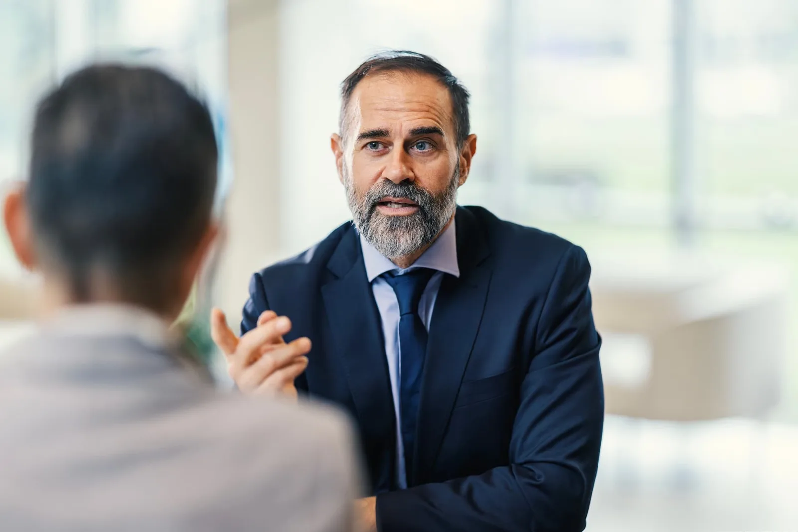 Two men in discussion across a table in a bright office