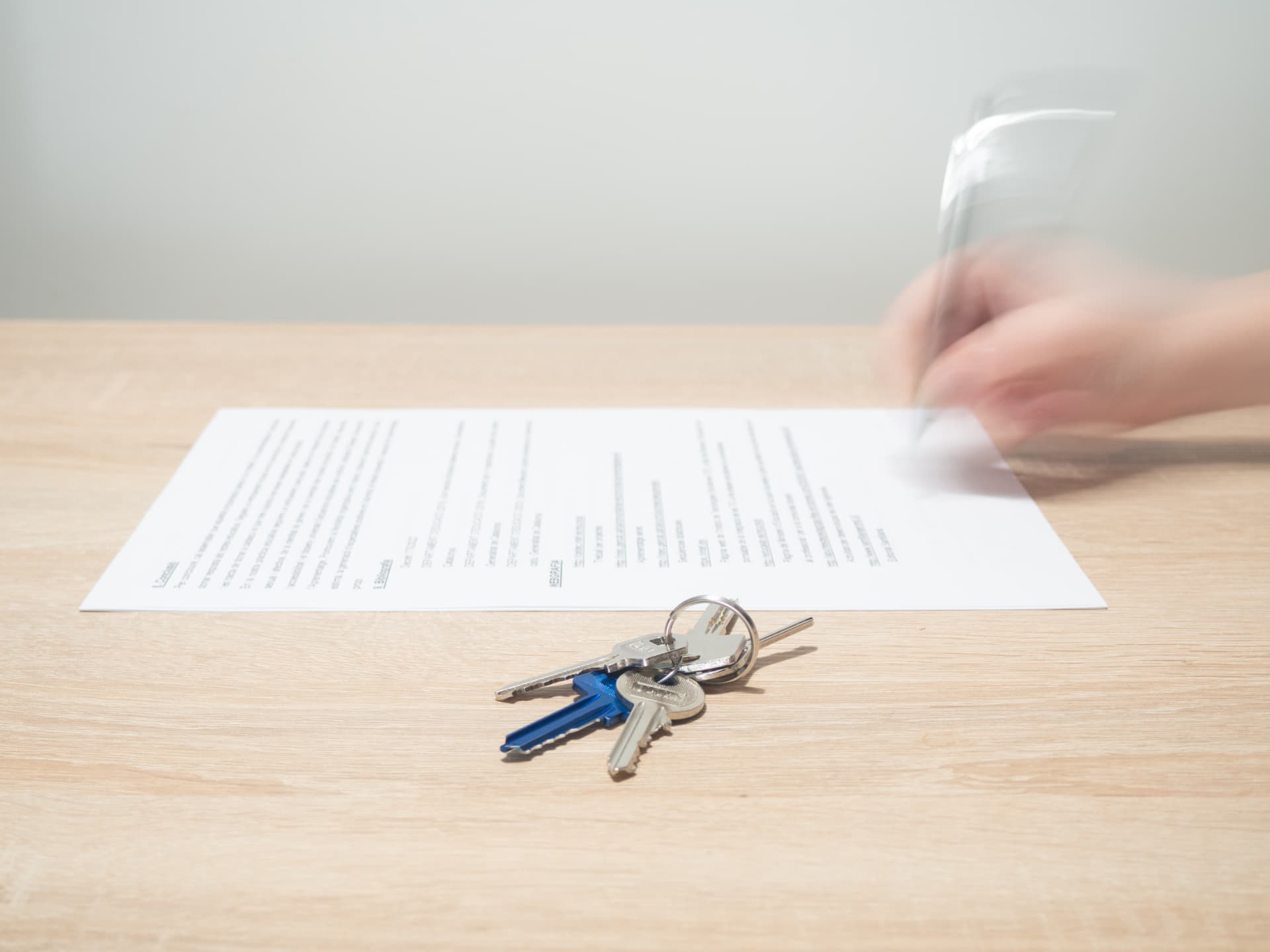House keys beside legal documents being signed during a property settlement.