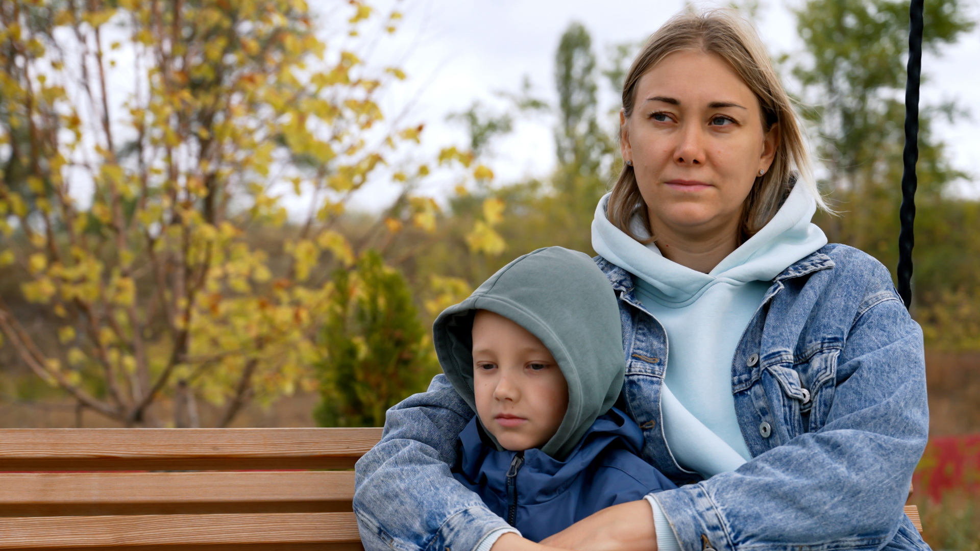 Mother and young child sitting together on a park bench