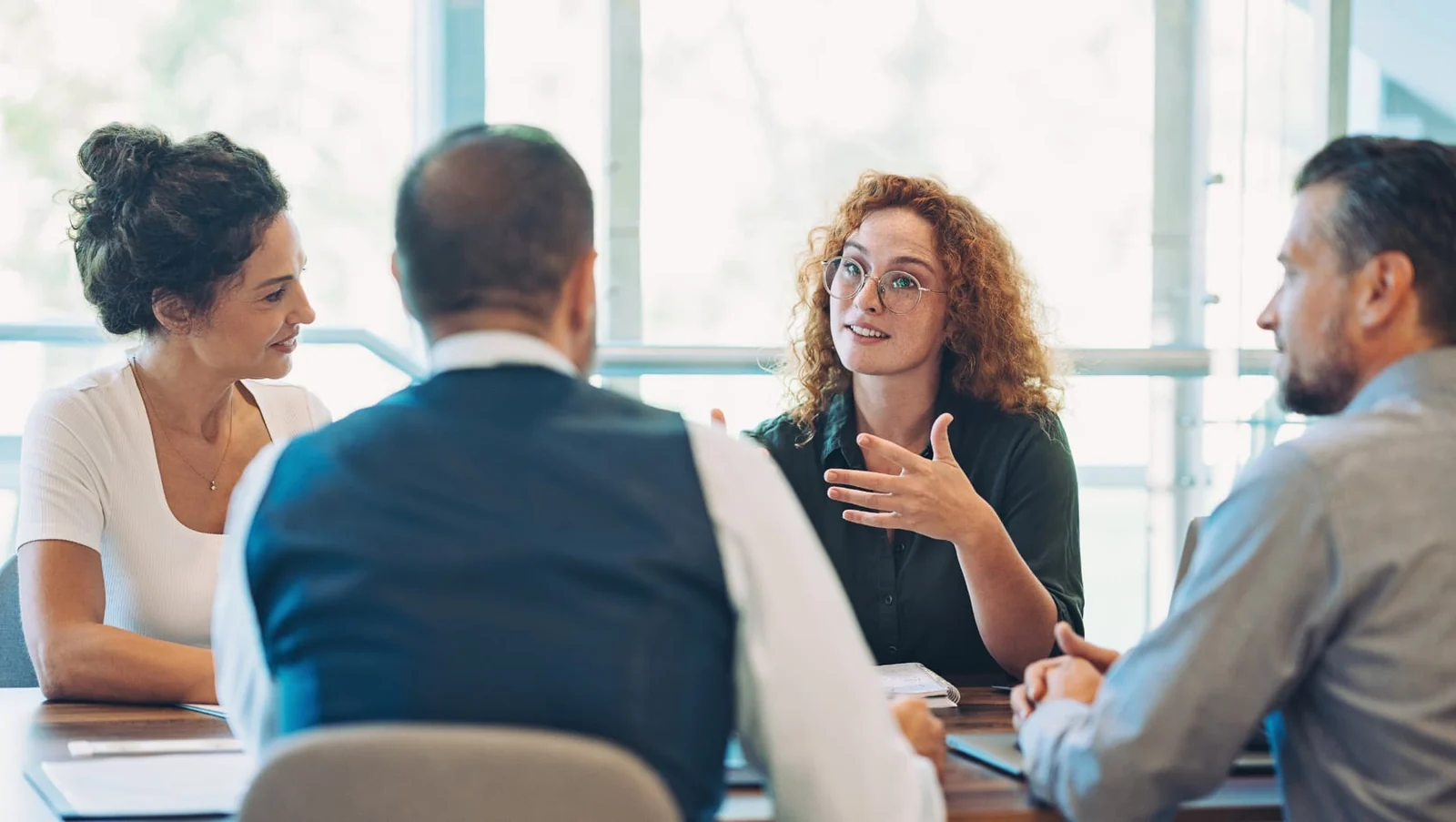 Four people discussing documents around a meeting table