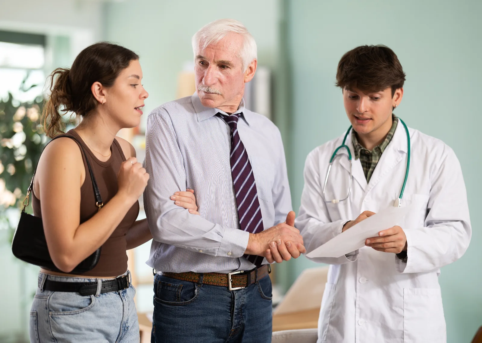 Older man and family member discussing medical documents with a doctor