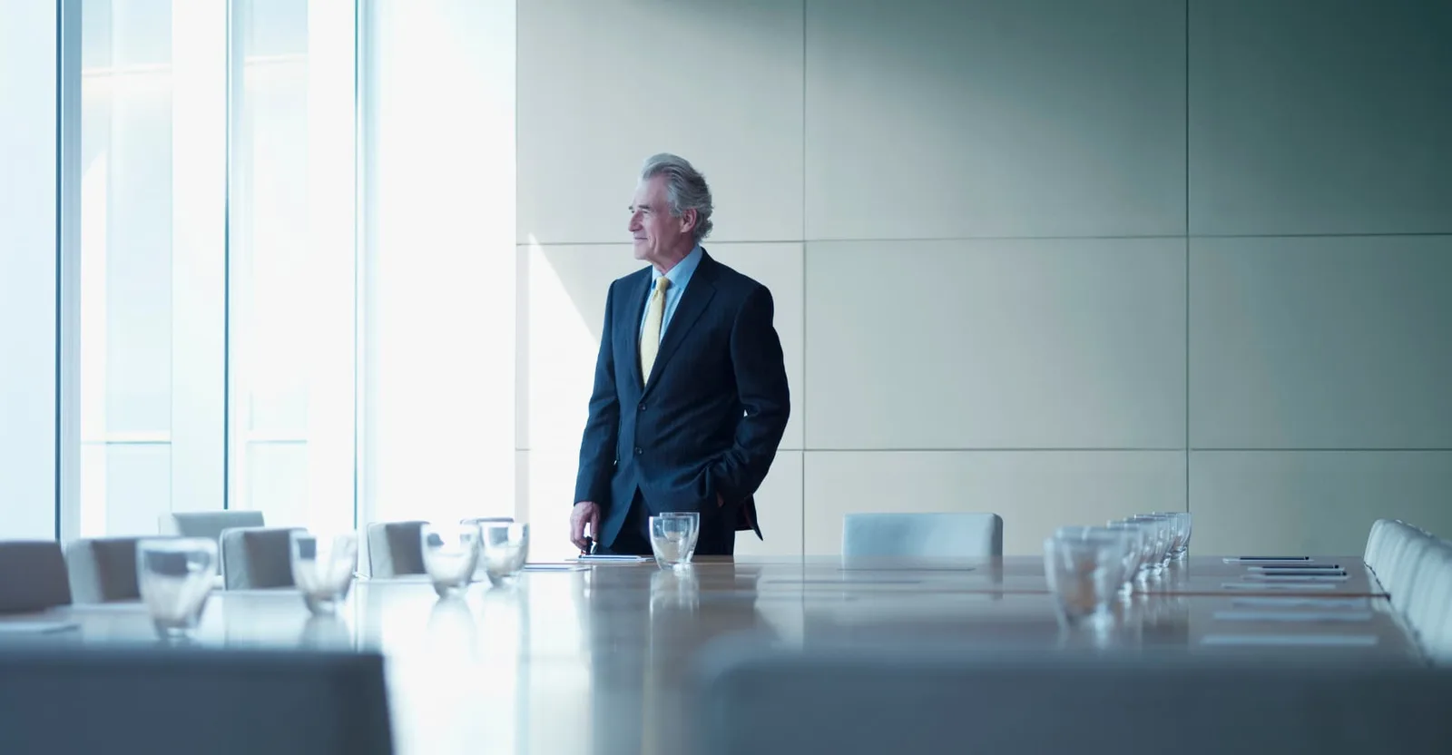 A businessman standing in a bright boardroom beside a conference table