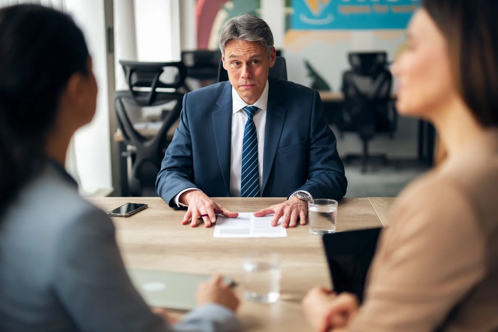 Three people discussing documents around a meeting table