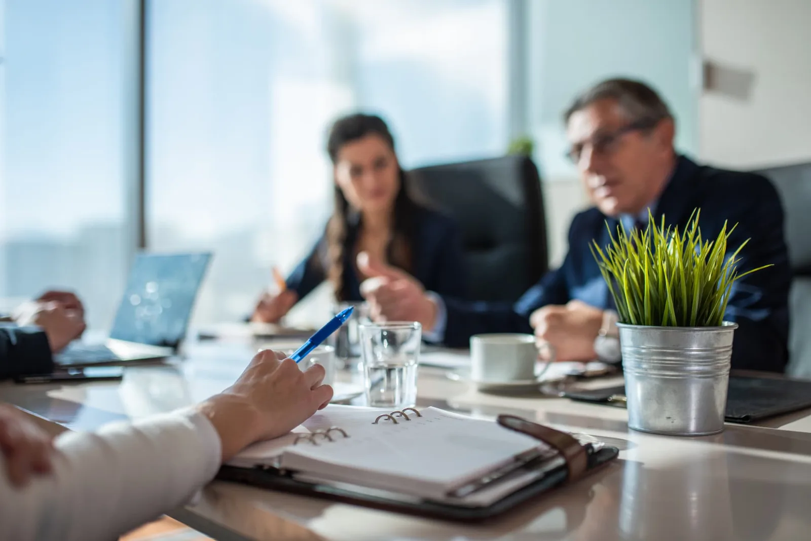 People in a business meeting around a conference table with documents and laptops