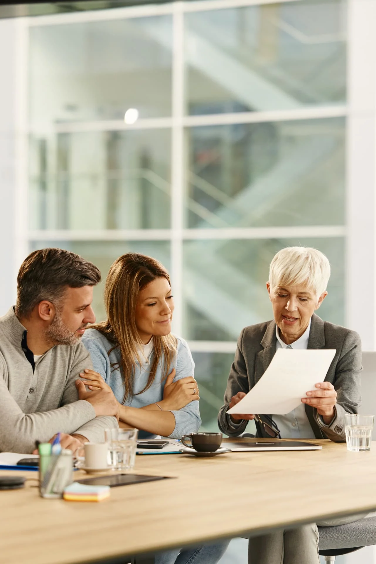 A senior lawyer reviewing property documents with a couple at a conference table