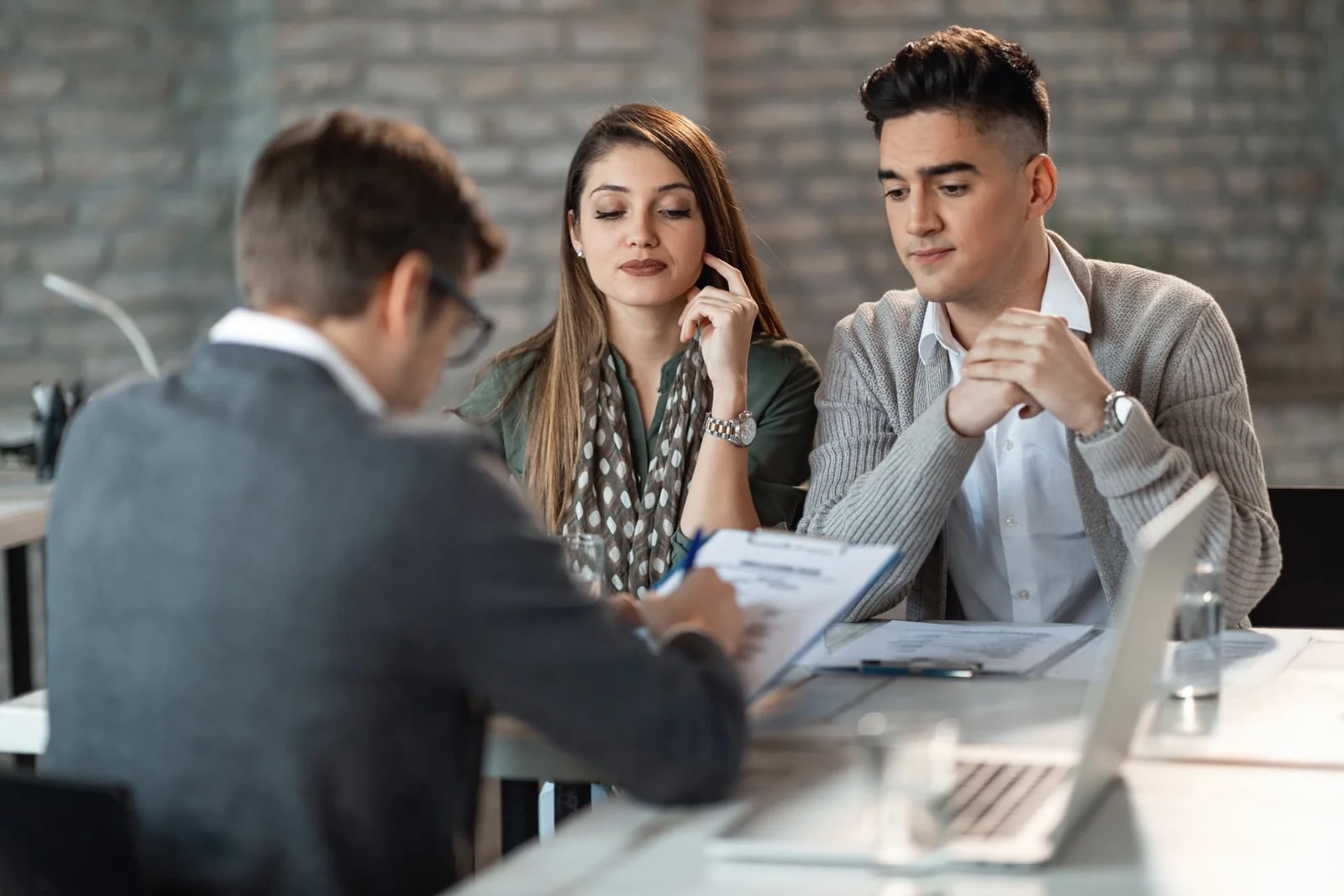 A couple consulting a lawyer across a desk during an office meeting