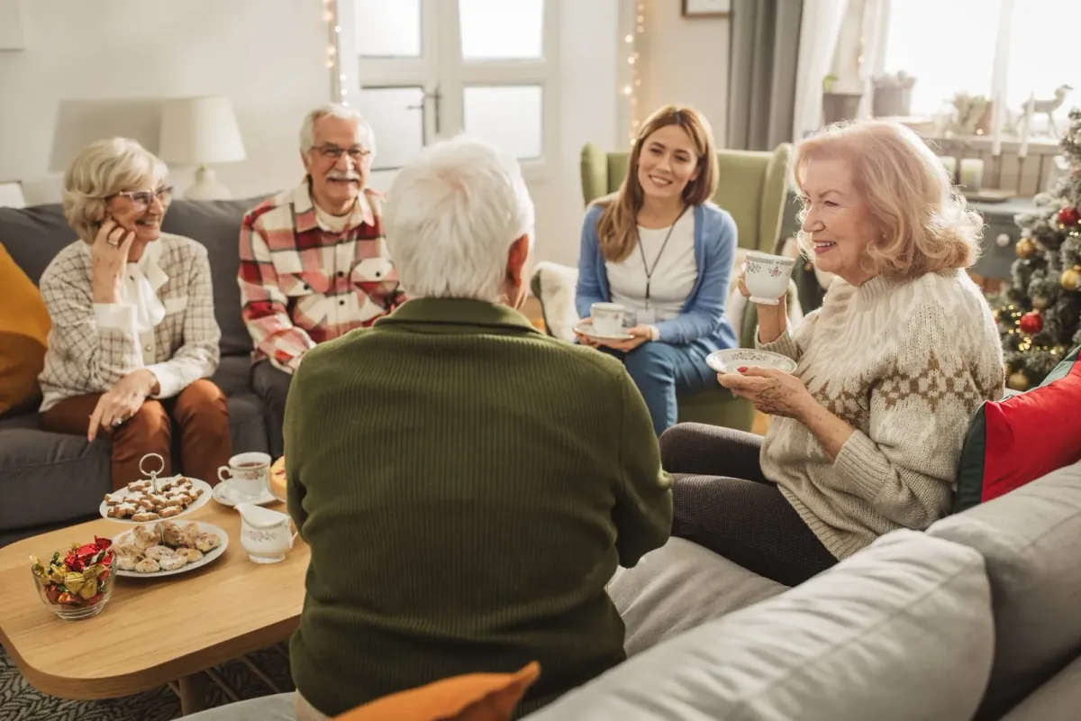 A family gathered in a warm living room sharing tea and conversation