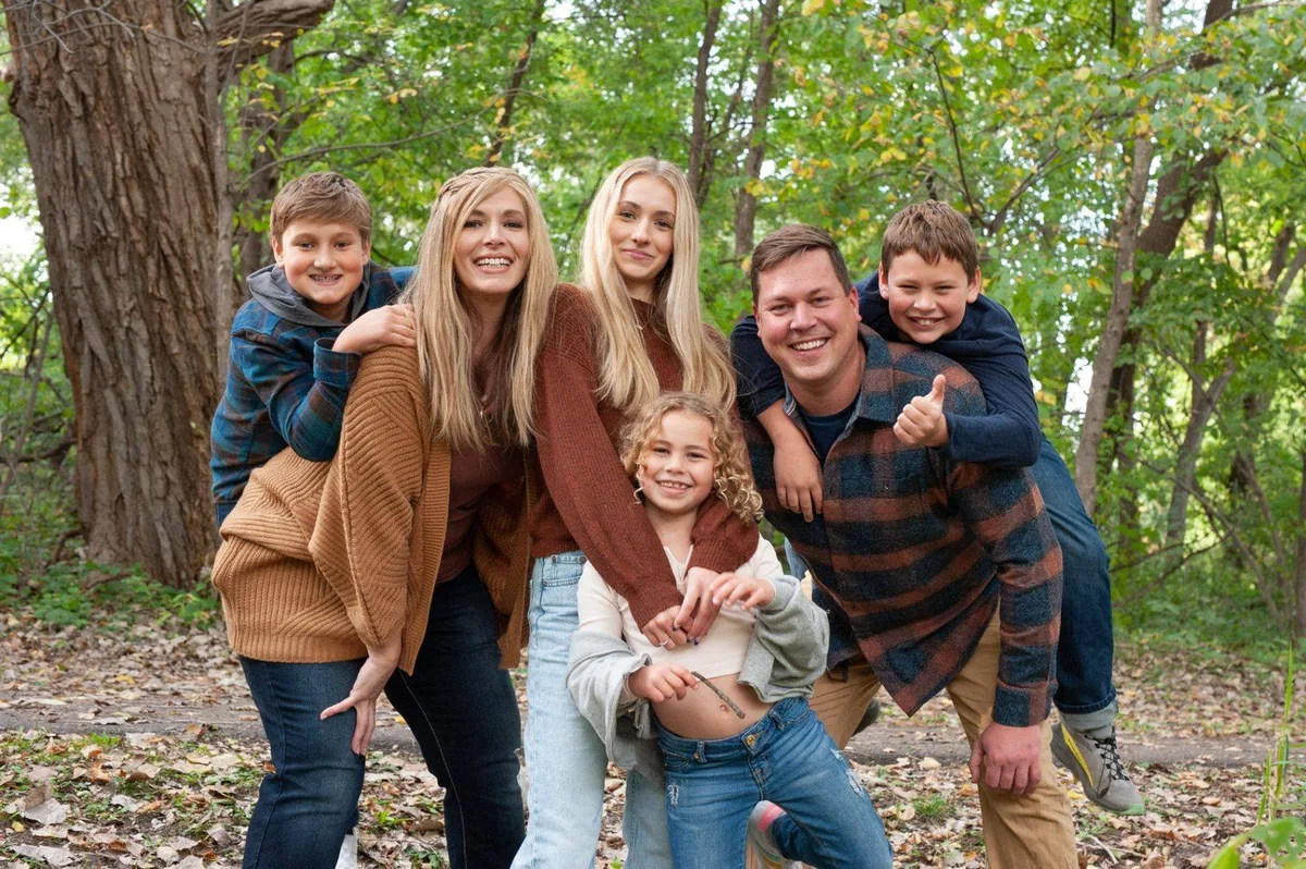 A blended family of six smiling together outdoors in autumn