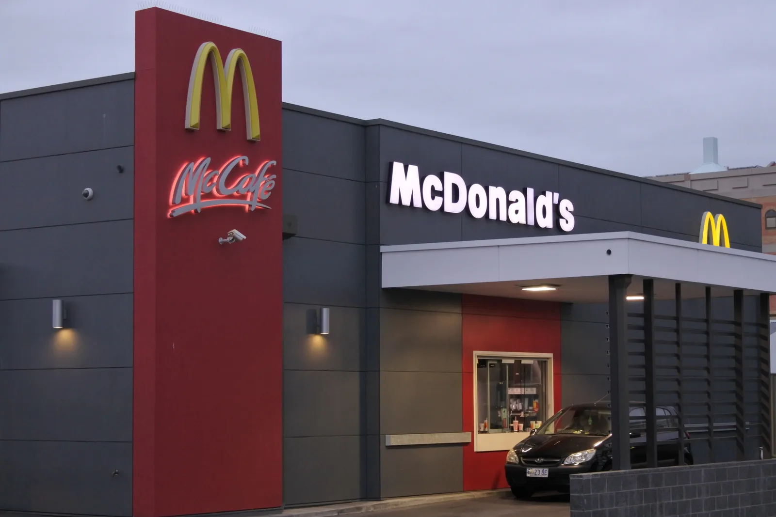 Exterior of a McDonald's franchise restaurant at dusk with illuminated signage and drive-through