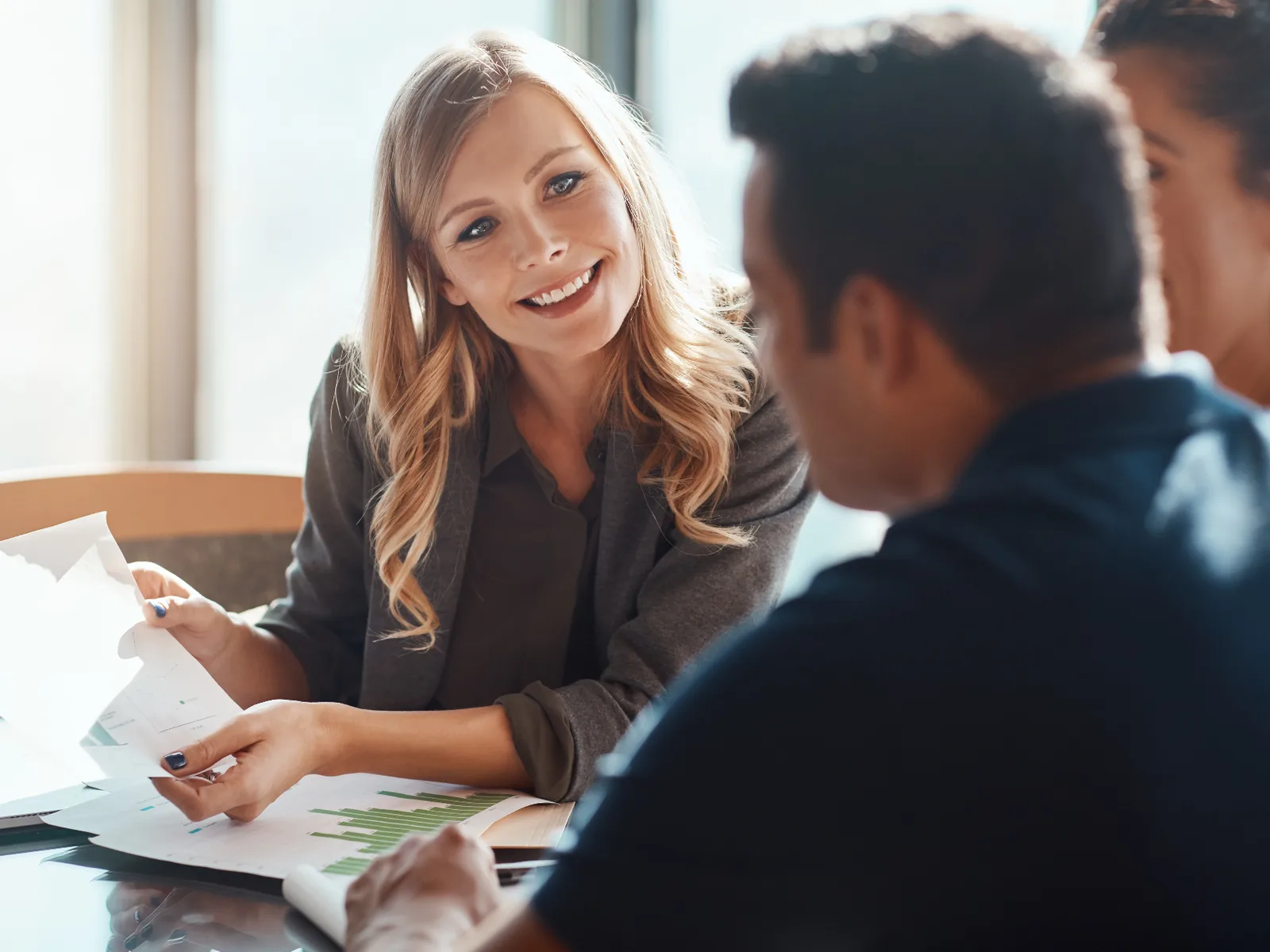 A Parke Lawyers commercial lawyer leading a strategy discussion with business clients, reviewing financial documents around a meeting table