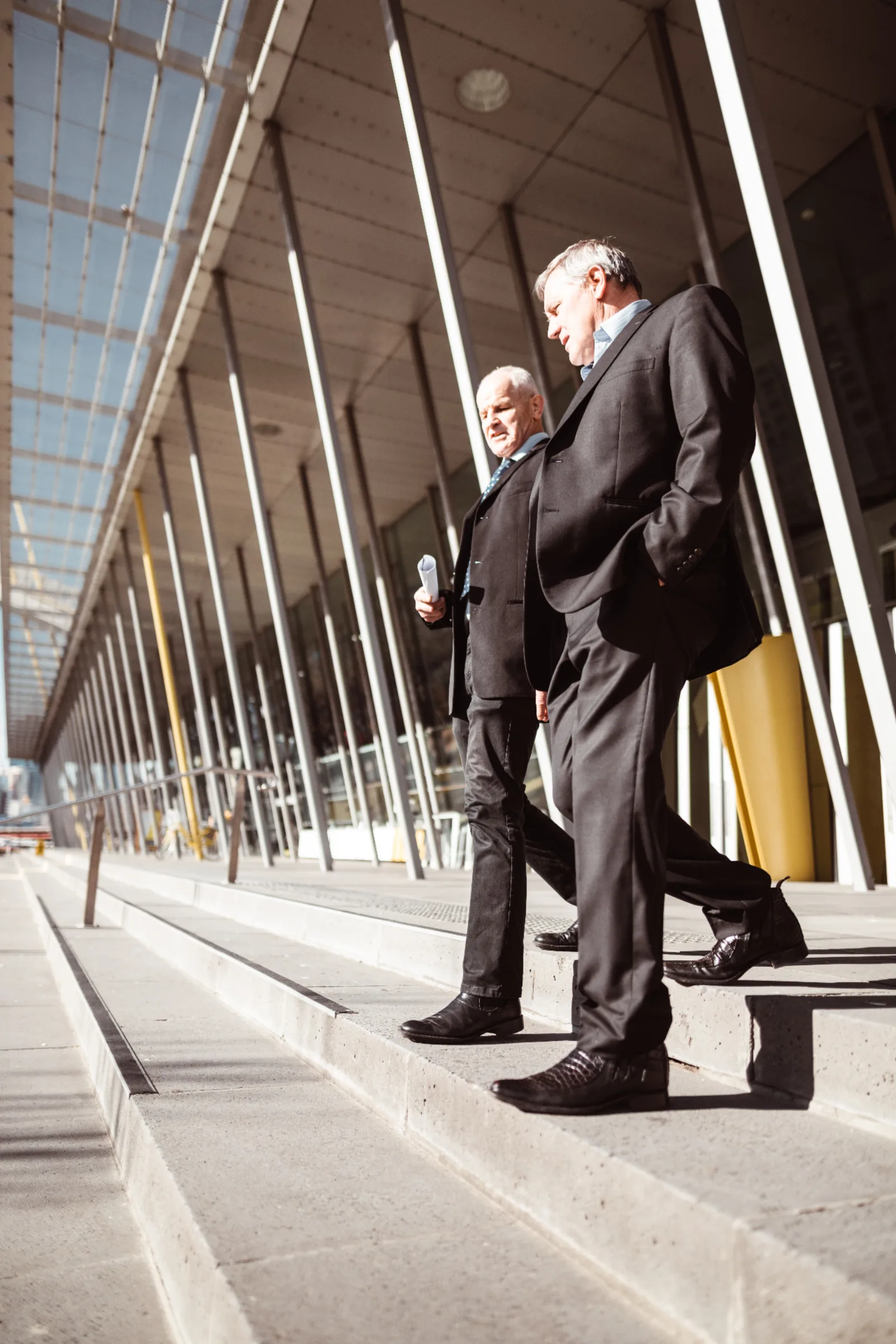Business owner and employment lawyer walking together outside a Melbourne office building, discussing a workplace issue